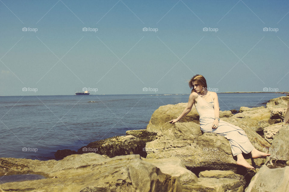 Woman sitting on rock at sea side