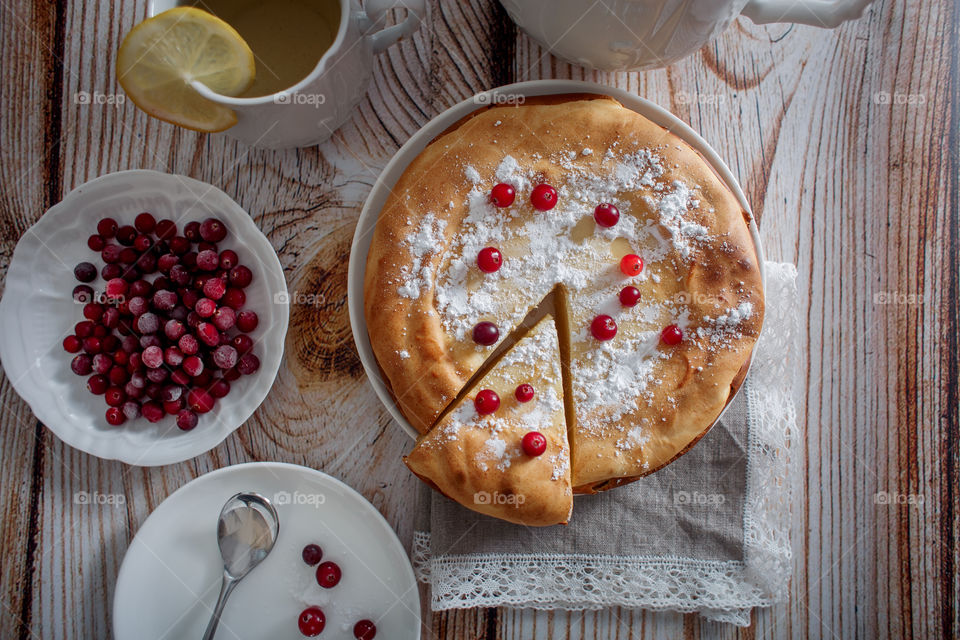 Cheesecake with cranberries and sugar on wooden background