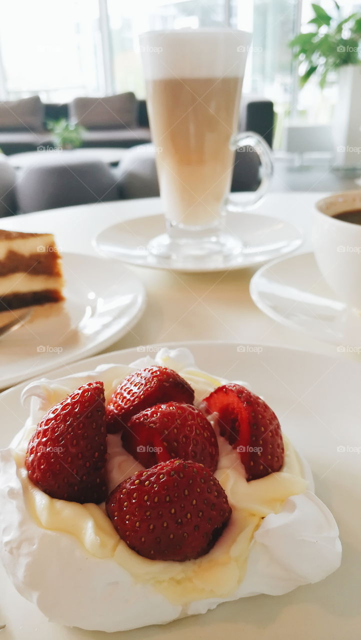 Meringue with strawberries and coffee latte