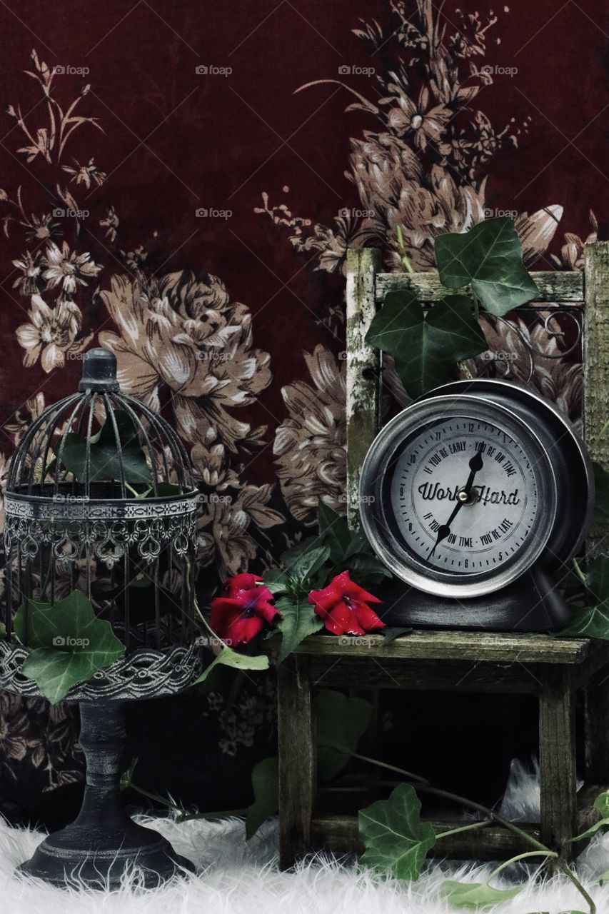 Antique clock and birdcage against antiqued flower background 