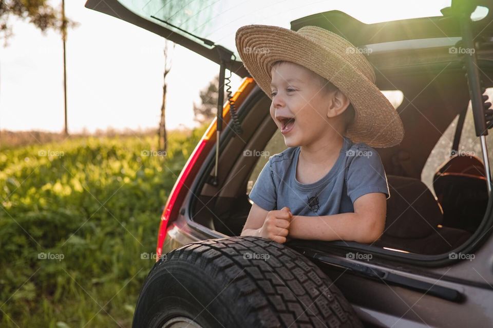 Little toddler boy sitting in car trunk