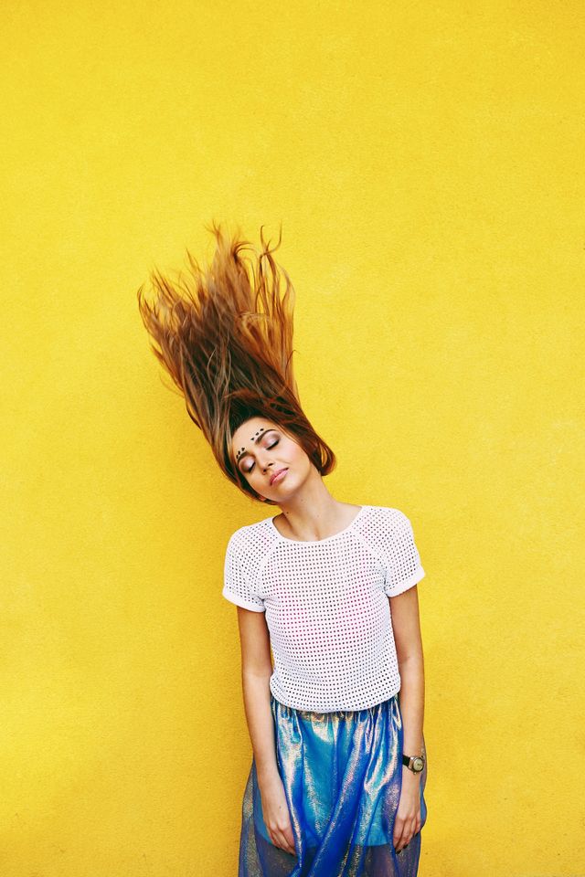 Yellow dreams . Attractive girl in an unusual skirt posing near a yellow wall