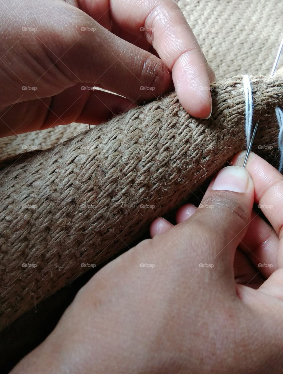 Close-up of hands sewing jute