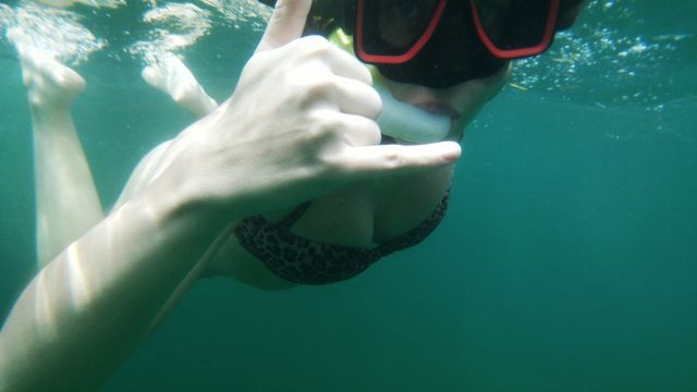 Female scuba diver showing shaka sign underwater