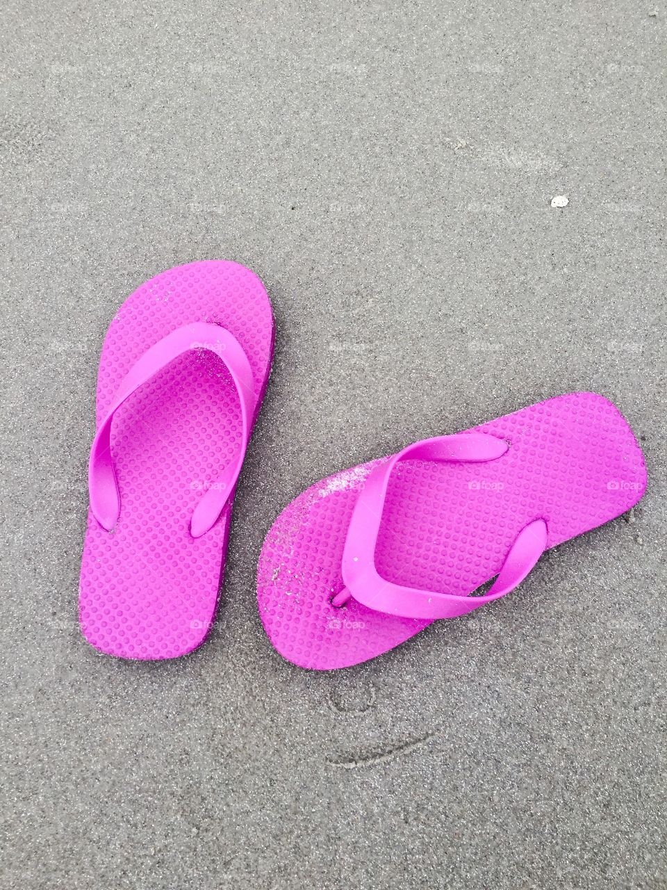Ready for Summer? Pink flip flop sandals on the beach.