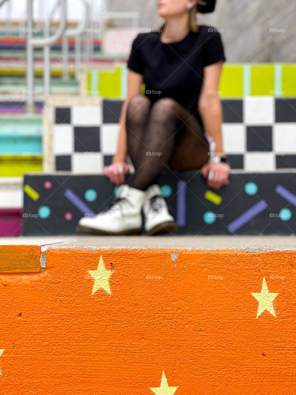 Urban out of focus person wearing Dr. Martens white 1490 boots on colorfully painted cement steps 