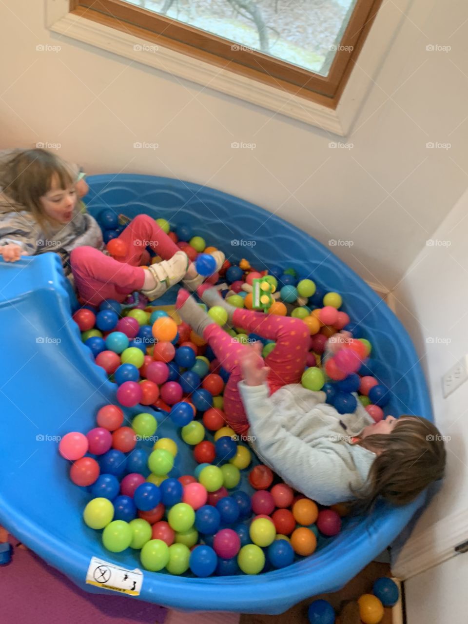 Biological sisters with Down syndrome in ball pit
