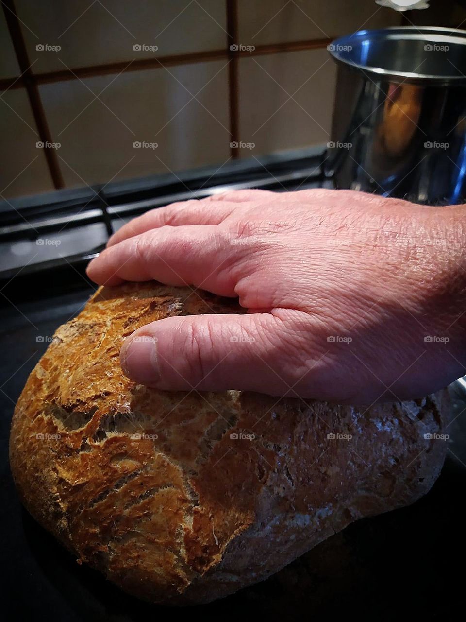 Homebaked bread.  A man's hand lies on the baked bread