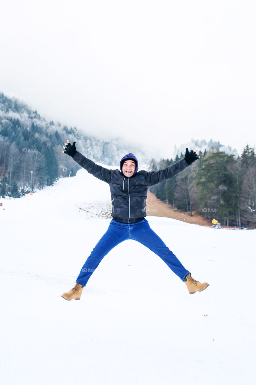 Man jumping on the snow. Mountain covered with snow. Winter time
