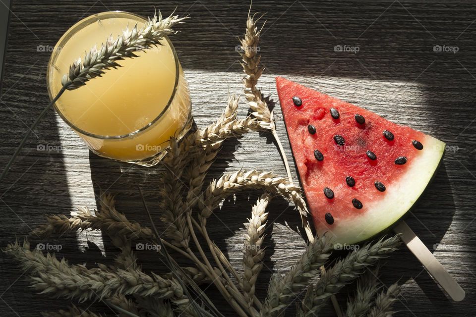 Portion of red watermelon with seeds in the form of a triangle on a wooden table surface