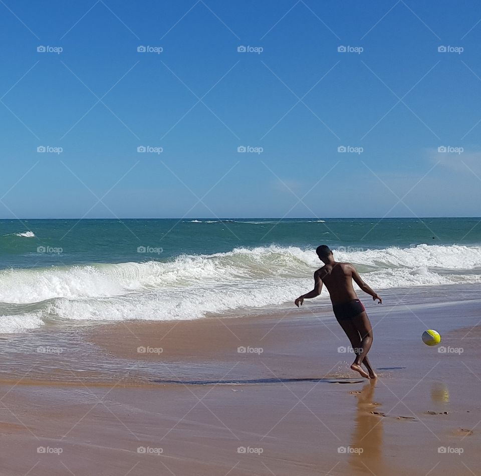Boy playing soccer on the beach - Brazil