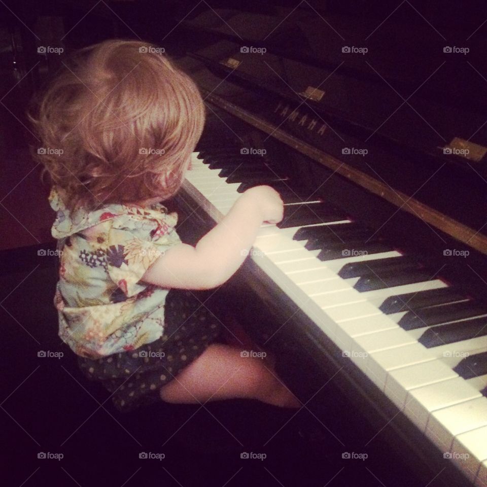Baby girl with full head of hair playing piano