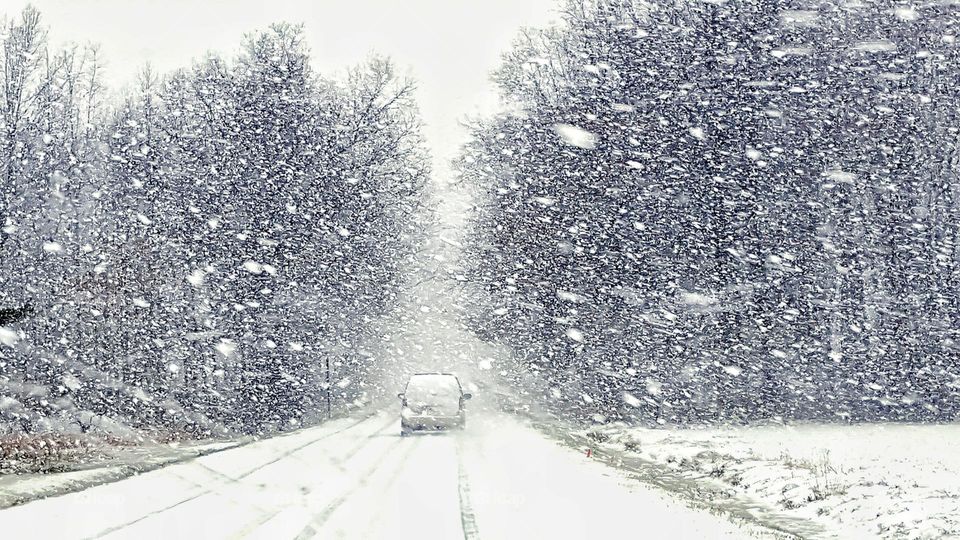 Extreme snowfall while driving along a country road. An oncoming car can be seen approaching.