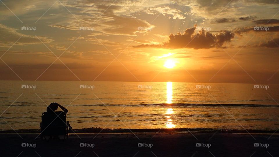 Pondering life and beauty of nature alone during a striking beach sunset