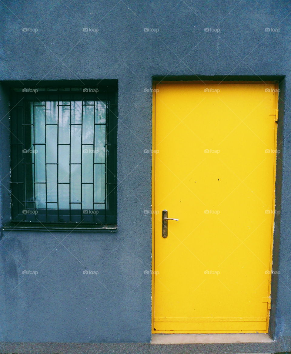 a yellow door and a window with a lattice in the building