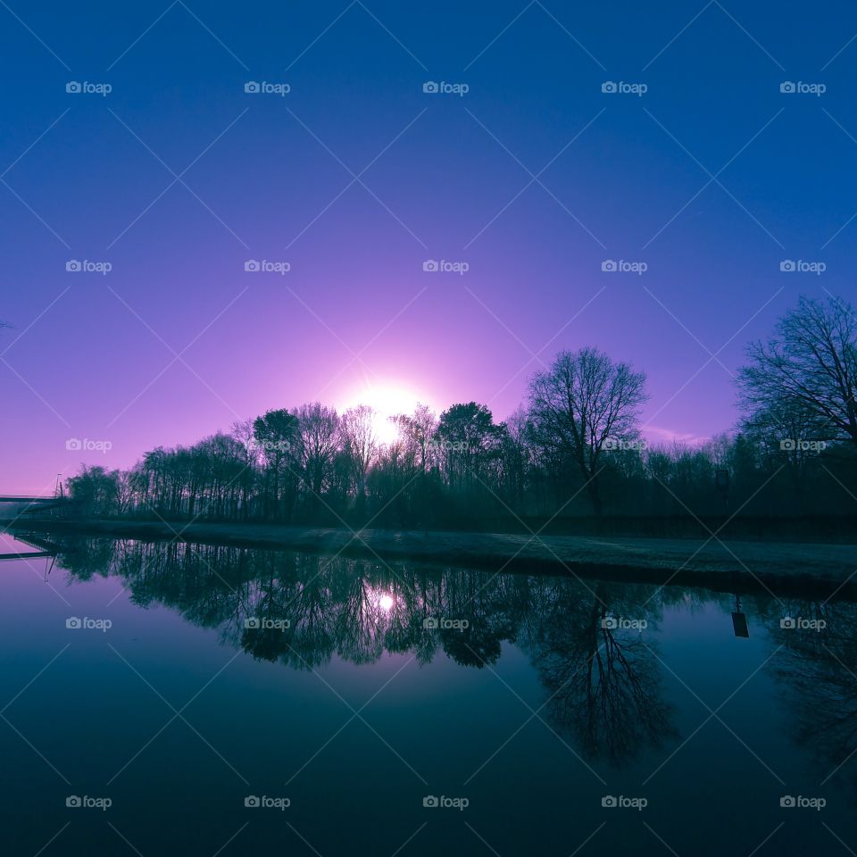 Countryside sunrise showing the colorful sky reflected in the water of the river 