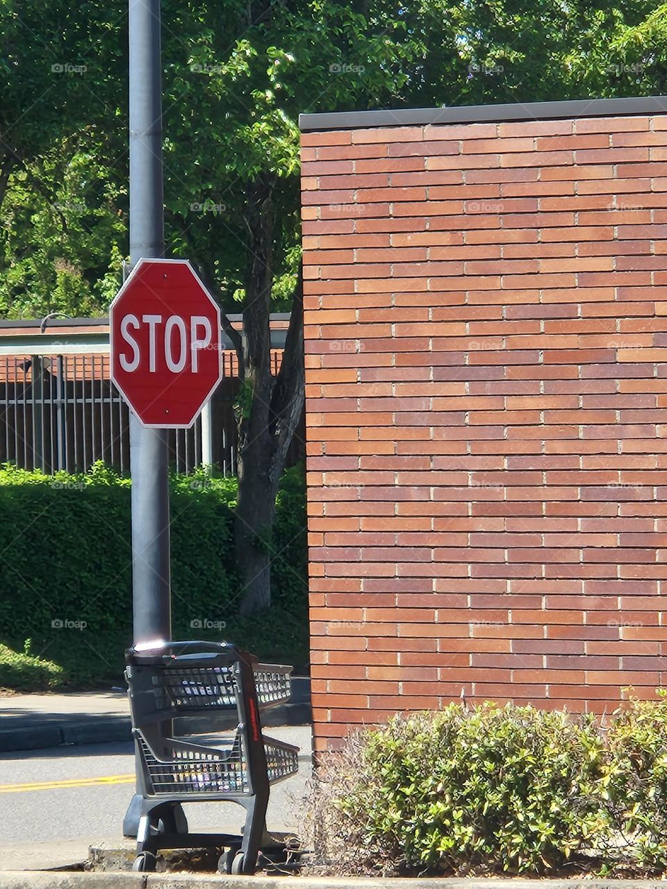 shopping cart by Stop sign post and brick building