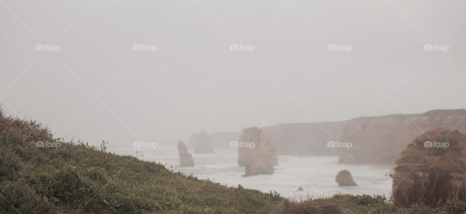 Misty ocean cliffs behind a grassy hill - 12 Apostles Australia 