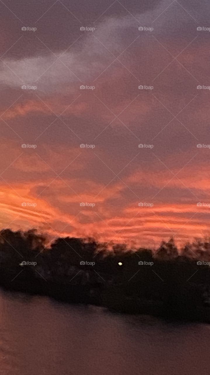 Sundown Completed Sky is opening up. Blistering Orange Slivers along with Yellows upper atmosphere bleeding down to the lower with Grays Blues Violets tops of high clouds getting into the act by opening up.