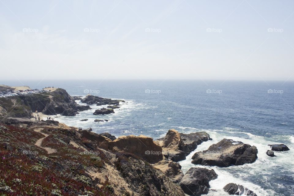 Sandy hill and a rocky shore by the sea in Half Moon Bay, California on a partially cloudy day