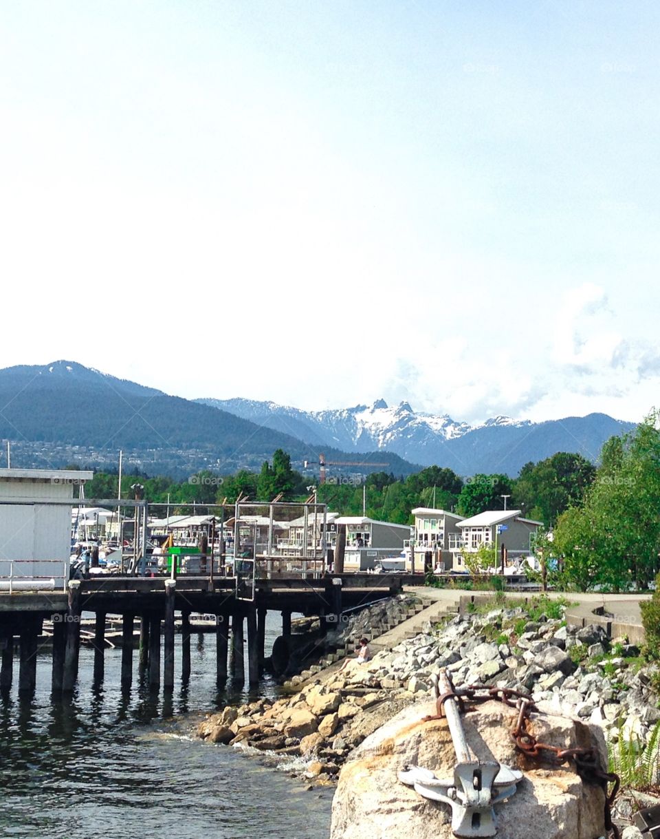 Floating homes and houseboats nestled in Marina  in north Vancouver with backdrop of snowy west coast mountains 