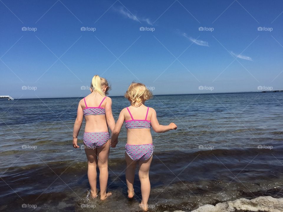 Twolittle sisters age three and five feeling the water at Ribban beach in Malmö.