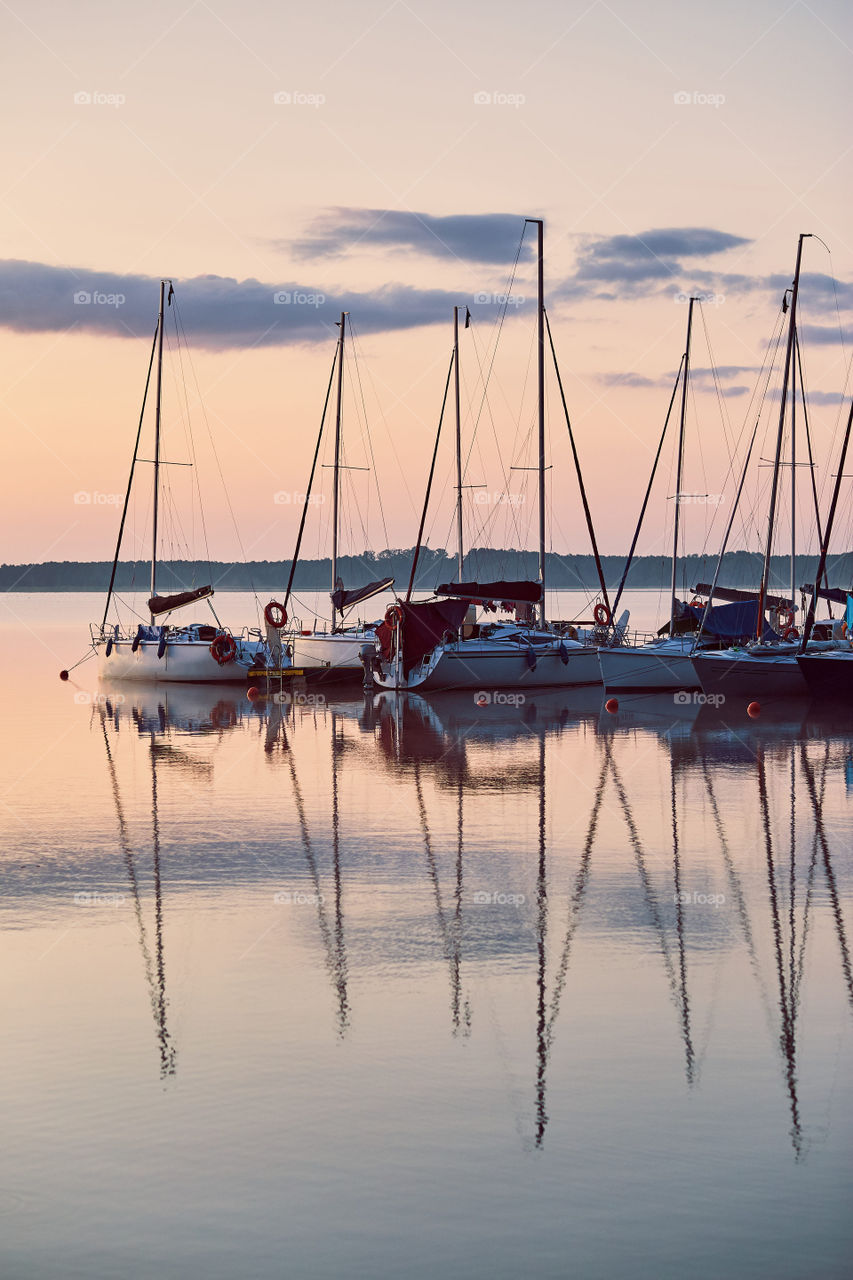 Yachts and boats moored in a harbour at sunrise. Candid people, real moments, authentic situations