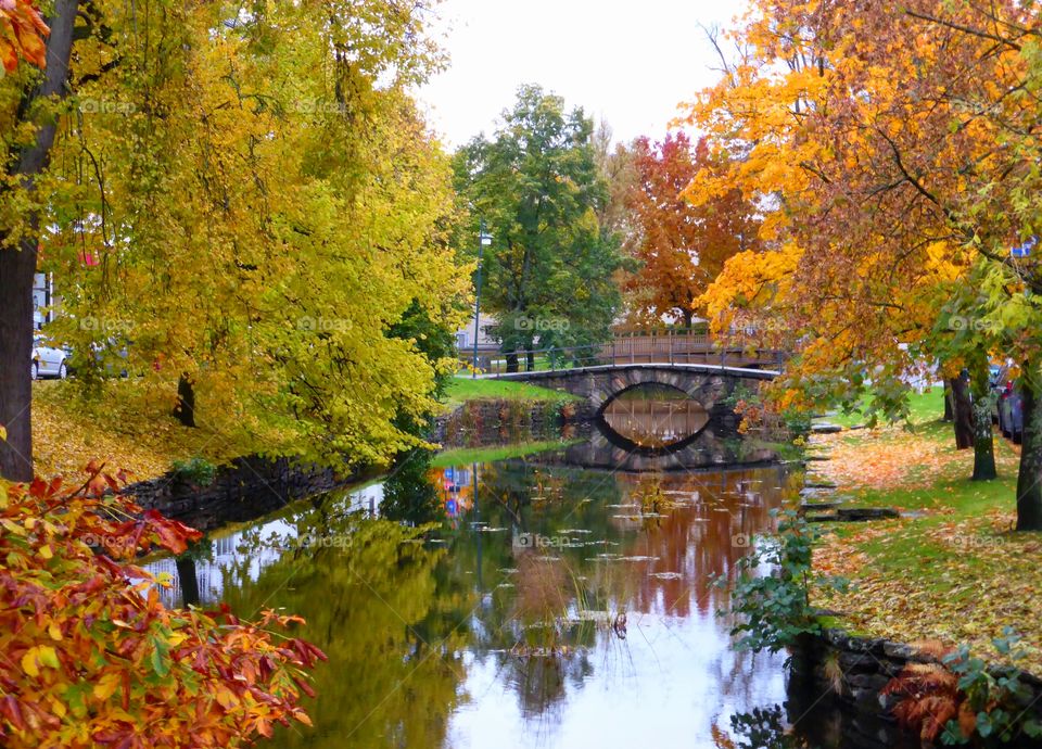 stonebridge and trees in autumn reflection in water