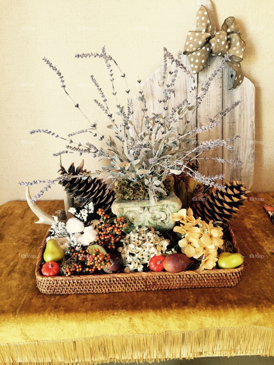 Fall celebration centerpiece with flowers and wicker basket with pine cones, gourds, fall leaves and flowers. 