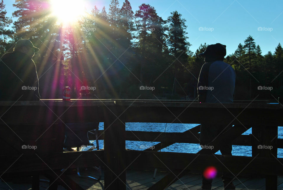 two men talking in silhoutte and a can of coke, sun rays, fishing, morning