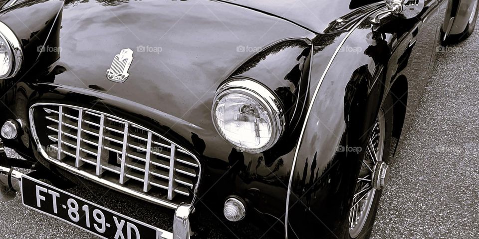 Black and white shot of a Triumph TR3's car front, grill and front lights at Cherbourg's car show