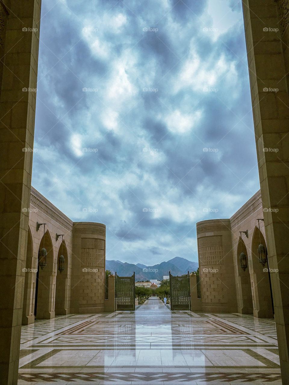 An Arabic architectural style building m. Dramatic skies with the mountains in the background.