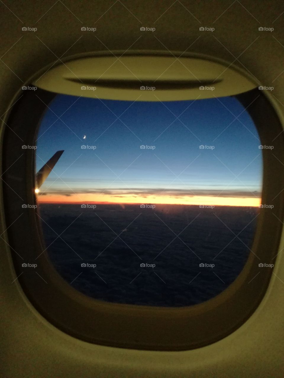 Flying: the moon and the sunset over clouds