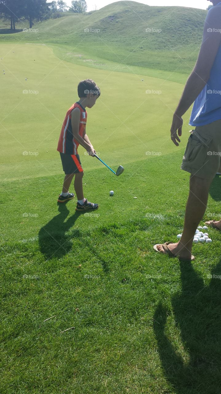 Golfing Lesson. Young boy learning to golf