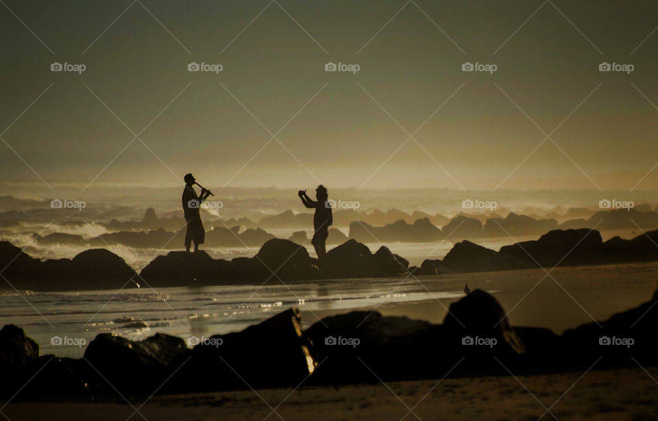 Silhouette of people and rocks at beach