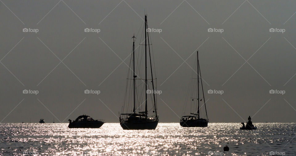 Sailing boats against the sunlight at the sunset 