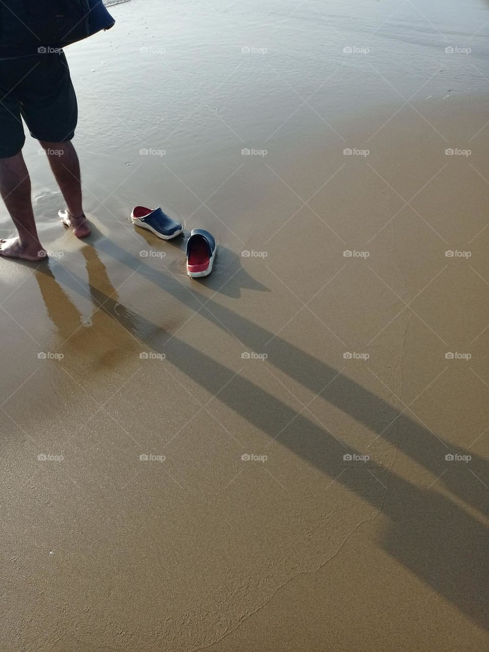 Young man standing on beach enjoying sunset with nice background shadow and beautiful shoes Red and dark blue colour closeup photo