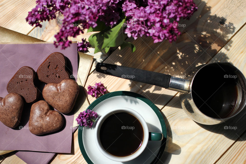 Coffee, hot drink, drink, grains, coffee beans, cinnamon, sticks cinnamon, lilac, flowers, purple flowers, bouquet, flowers in a vase, vase, rest, morning, work, cafe, restaurant, Gingerbread, cookies, dessert. bakery products. Heart, sweetness, dessert in the form of heart, chocolate dessert