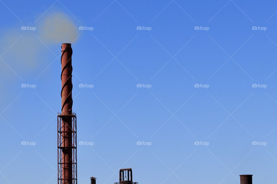 Iron ore steel industry smelter chimney stack blowing plume of smoke into atmosphere 
