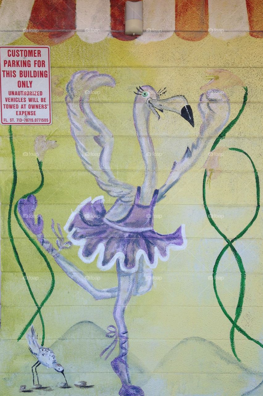 Mural of a pink flamingo ballerina on the side of a building