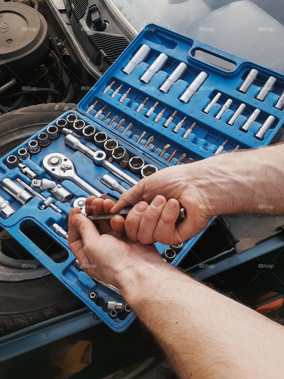 Photo of a mechanic's working hands and his toolbox
