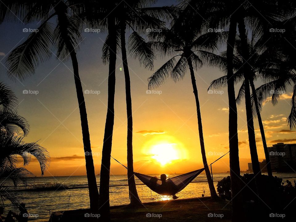 Silhouette of a person resting on hammock at beach