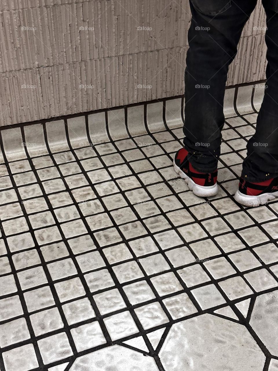 square off white commercial tile floor paired with thin ridged rough finish pinkish beige tiles in a bank showing partial image of person wearing dark denim and red athletic shoes 