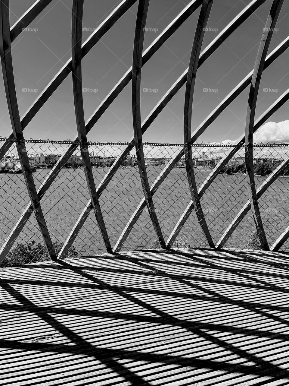 Black and white monochrome photo view to the sky and sea through modern construction rhombus cells of cage building