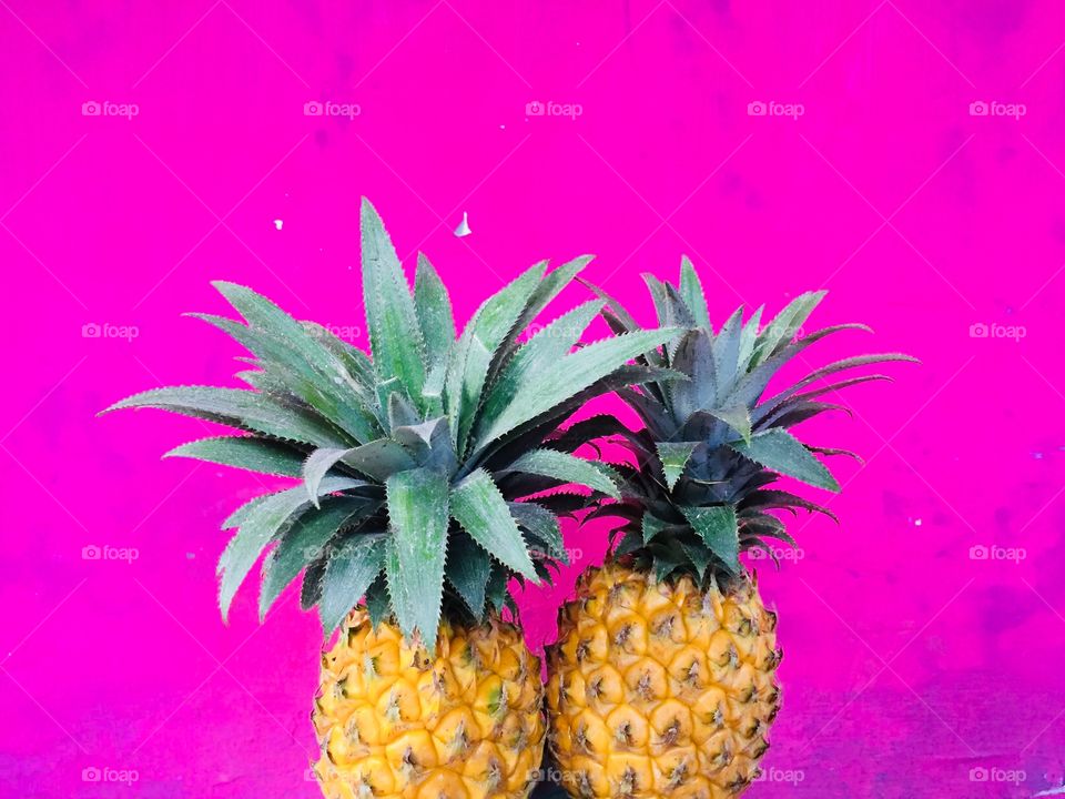 A yellow pineapple combination with a pink background