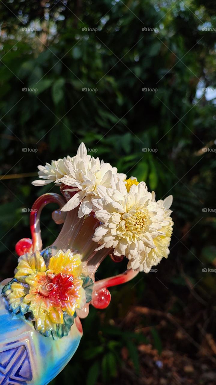 Beautiful white flowers in a colourful flowerpot with a flower sculpture