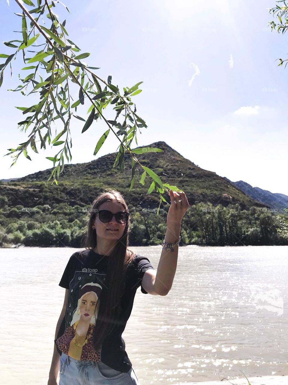 Portrait of Beautiful woman holding a tree brunch near the lake and mountain 