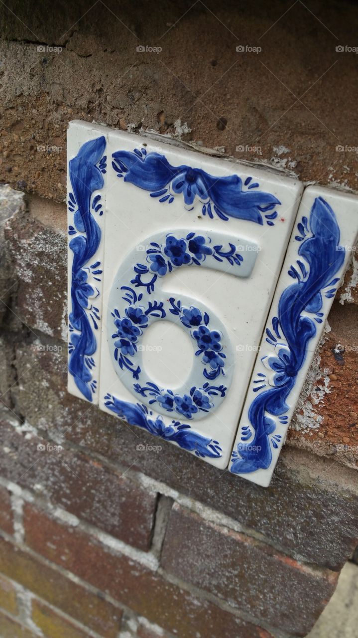 number 6 . 
written number "6" fine China tiled sign on a stone wall. 
house number six
blue fine China
tiles
tiled
no: 6 no; 6