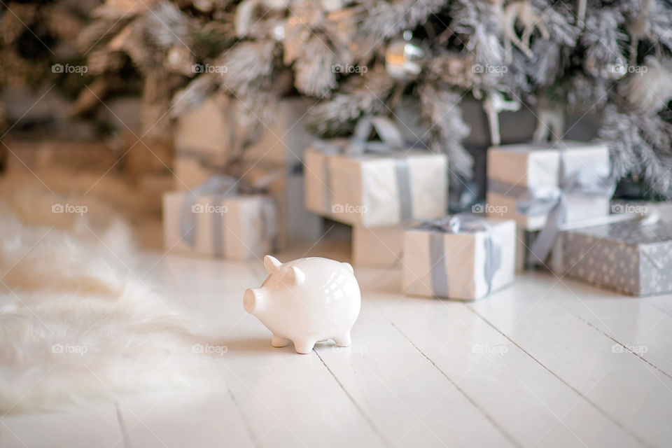 piggy bank with 100 dollars banknote in festive New Year atmosphere of scenery.  Magical bokeh with Christmas tree and bright lights.