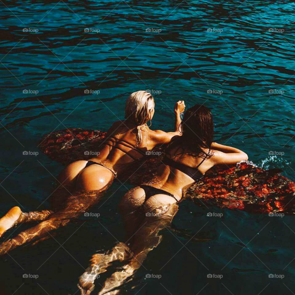 Rear view of women floating on surfboard over the water